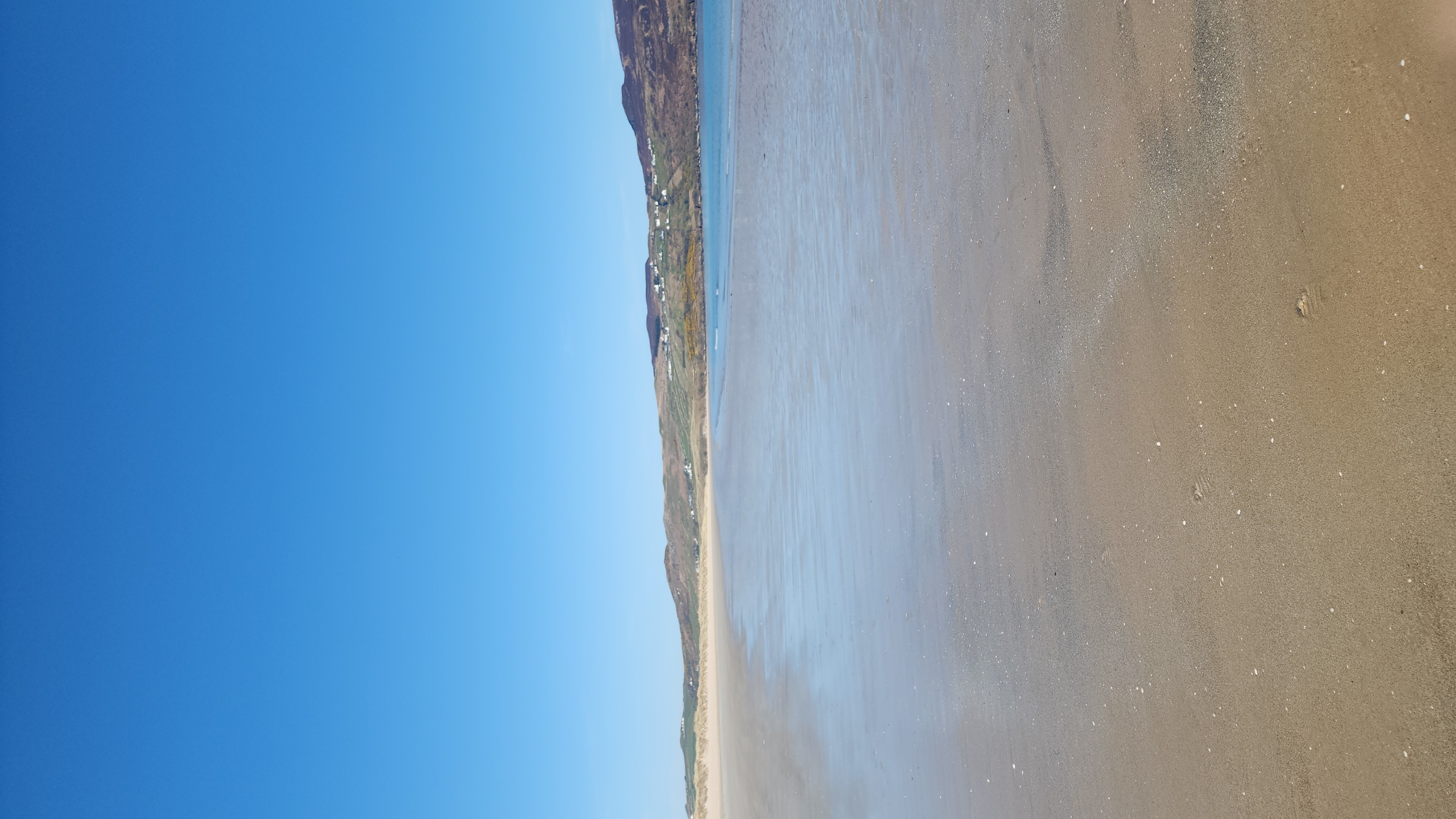 A wide open sandy beach beneath a clear blue sky