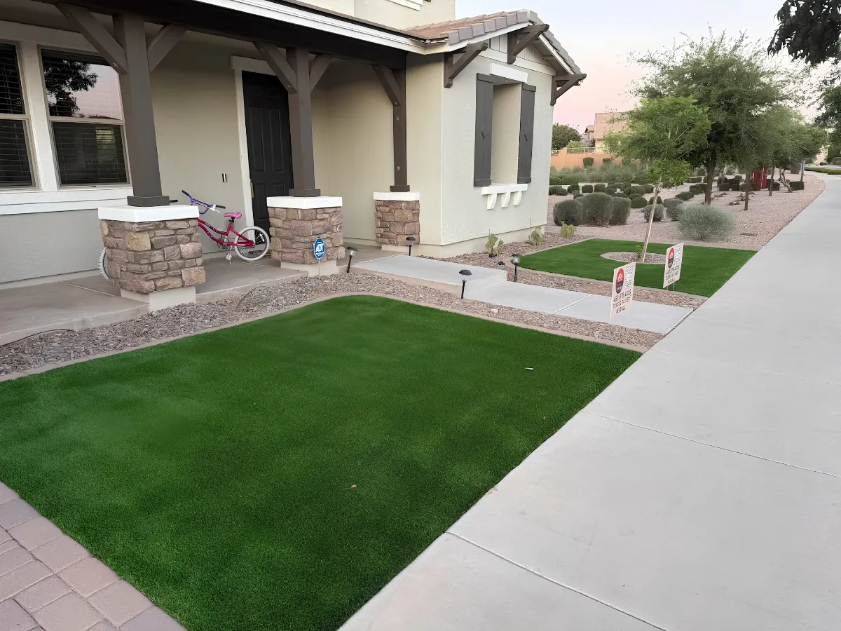 A modern backyard features a large section of vibrant green artificial turf bordered by a tidy gravel path.