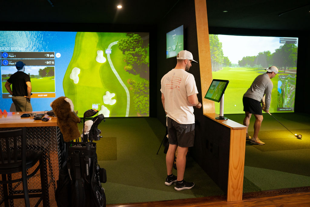 Two players competing on the golf simulator at Art of Flight Golf