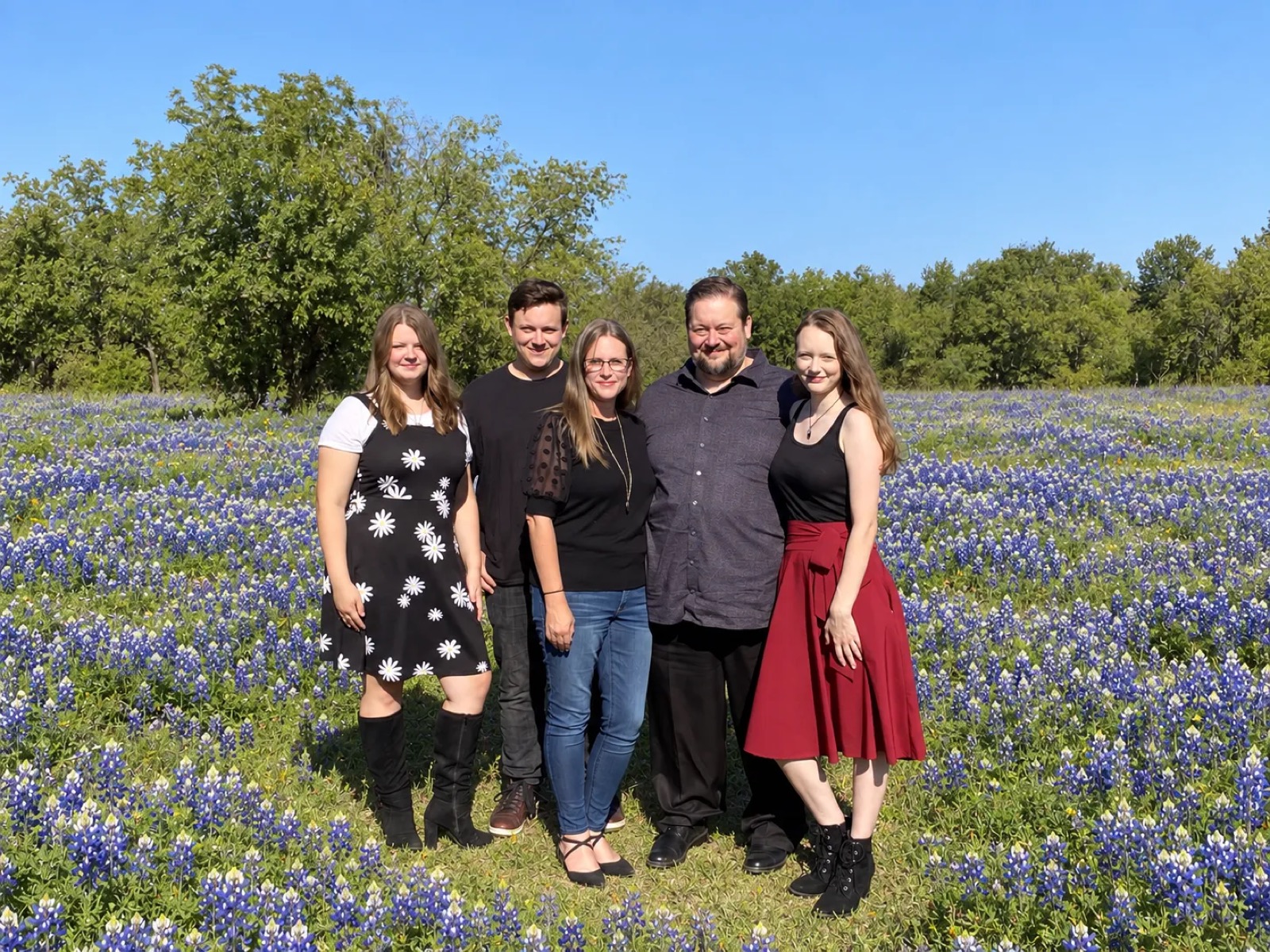 Neil, Jennie, and their three kids standing in a field of bluebonnets