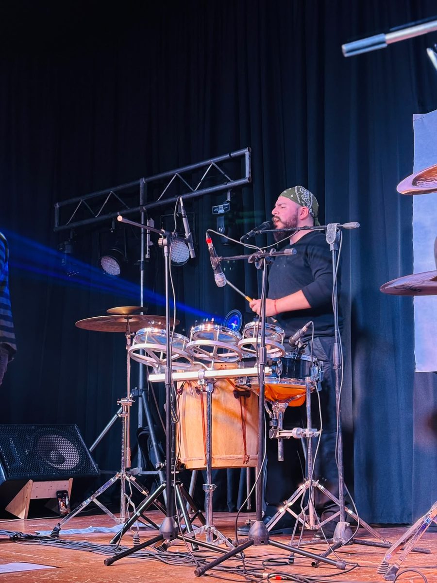 Simón Oviedo tocando la percusión en el escenario de un festival