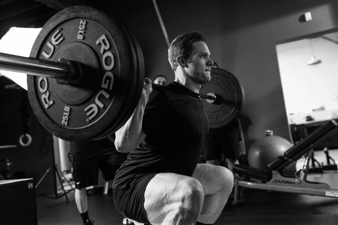 Steve Lutz performing a barbell squat in the gym.