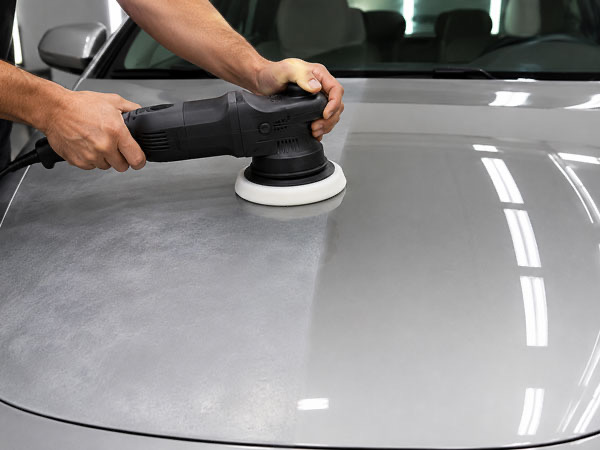Paint correction in progress on silver sedan hood before ceramic coating application