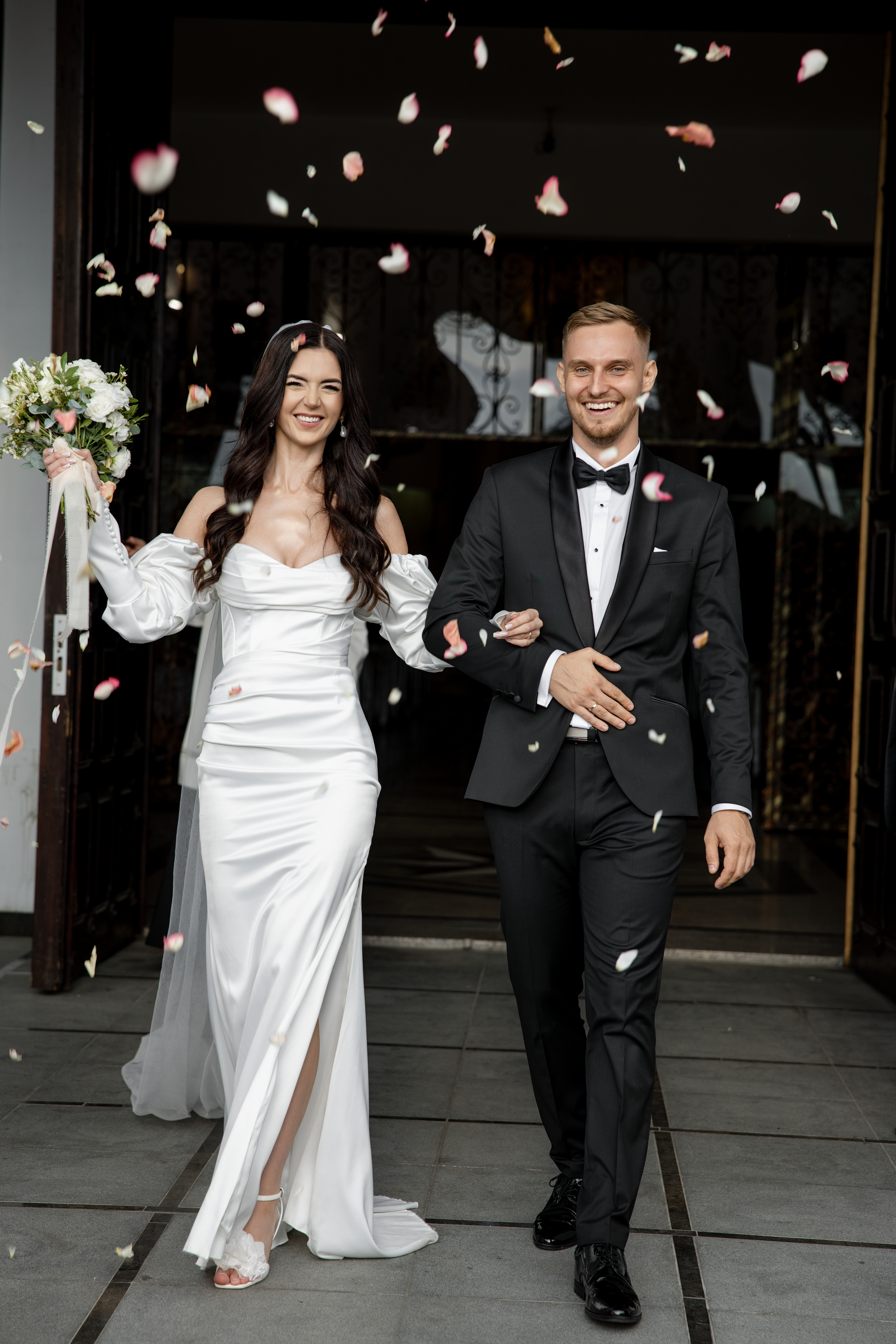 Newly married couple leaving a Warsaw church as guests throw rose petals