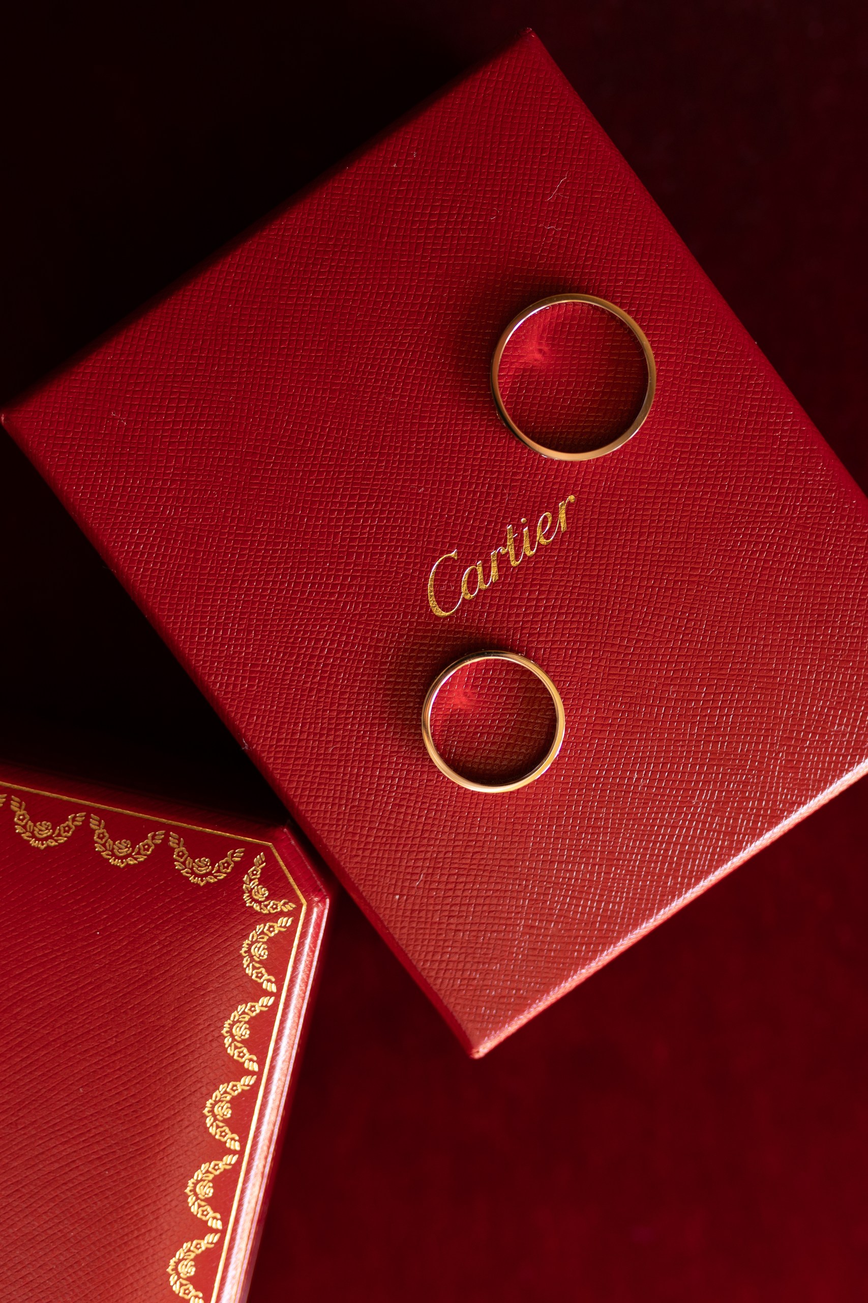 Gold wedding bands displayed on red Cartier boxes – luxury Milcha detail photography in Dubai by Lubov Lisitsa.