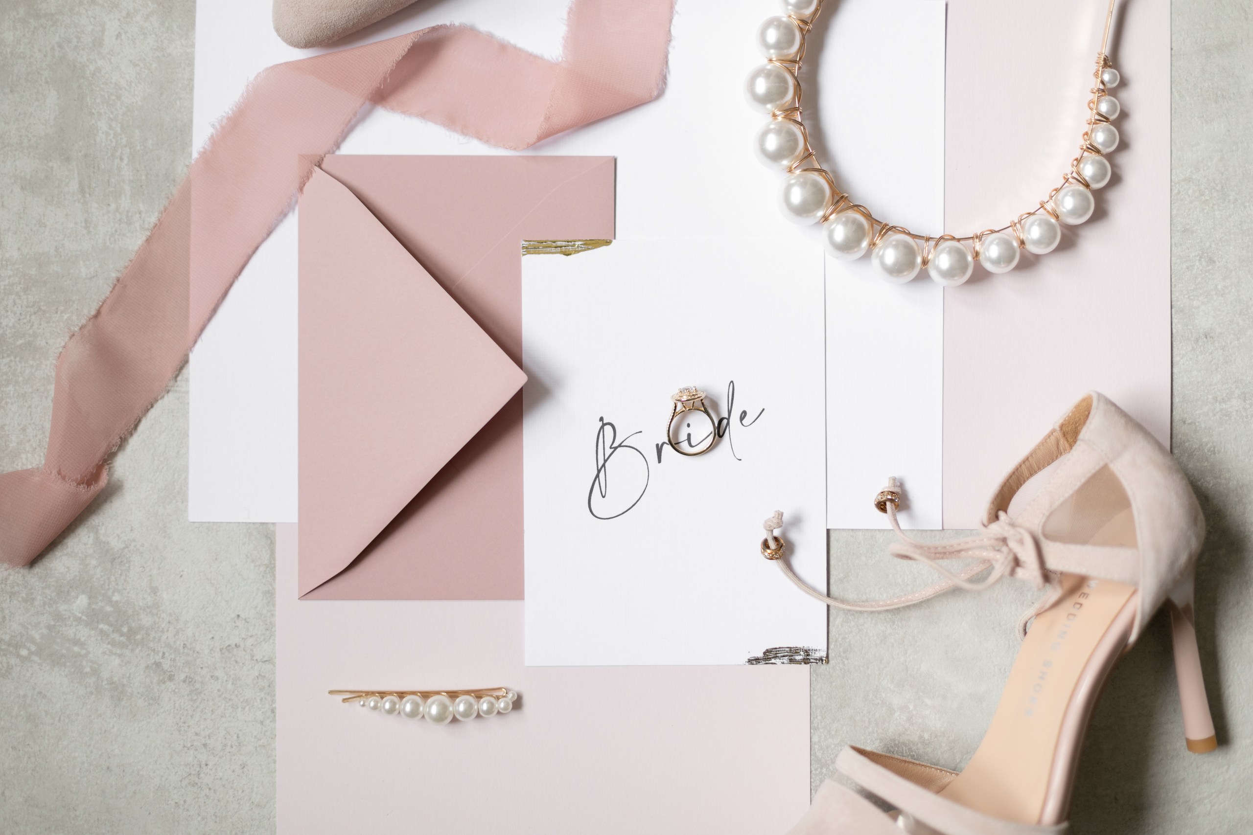 Blush stationery, engagement ring, pearl jewellery and bridal shoes – elegant Milcha details photographed in Dubai by Lubov Lisitsa.