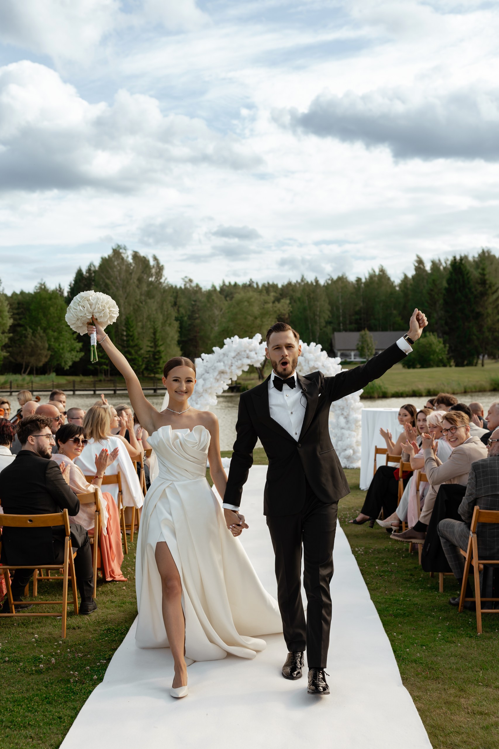 Newlywed bride and groom celebrating after an outdoor wedding ceremony, photographed by Warsaw wedding photographer Lubov Lisitsa.