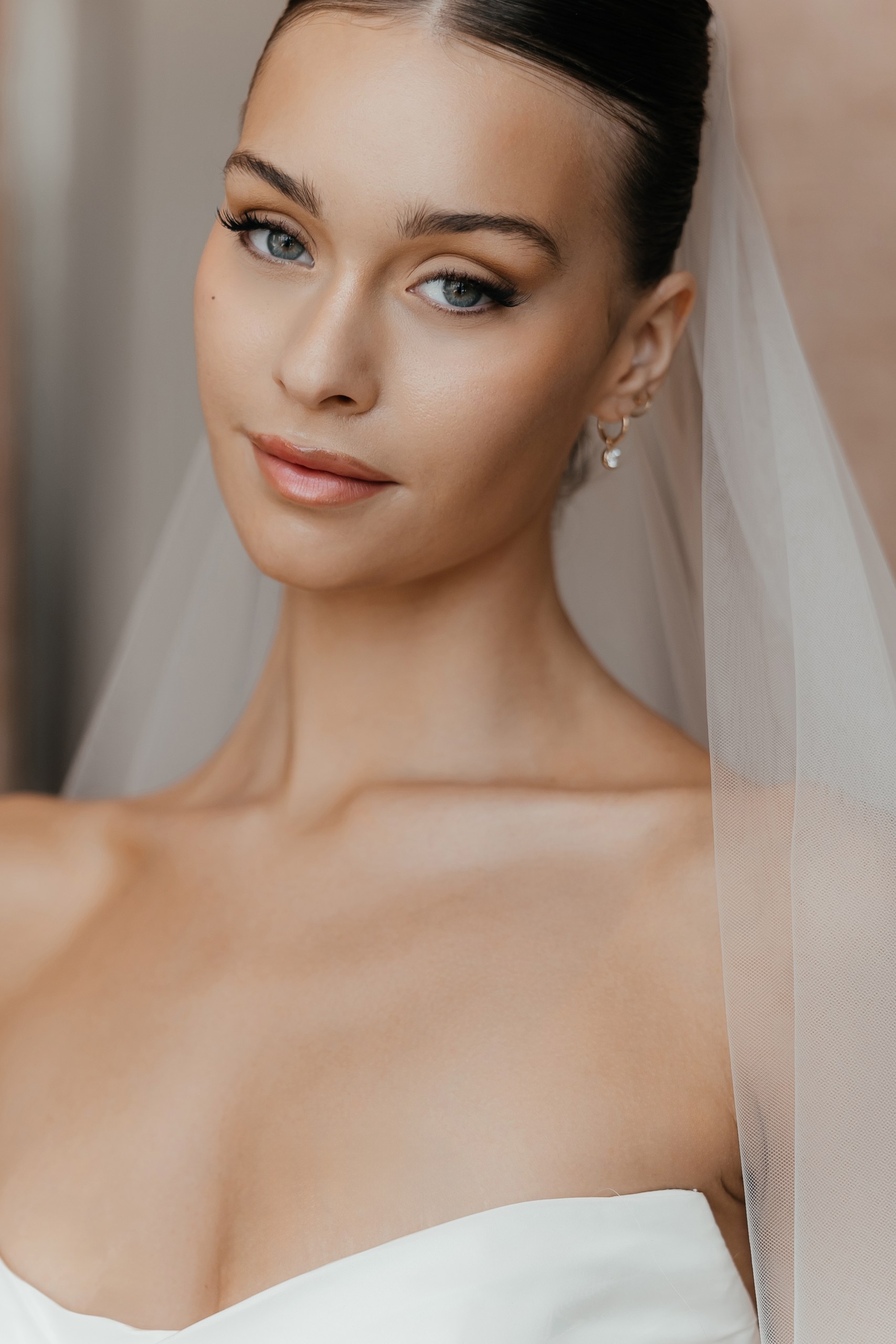 Close-up bridal portrait showing soft makeup, a sleek hairstyle and a sheer veil at The Lana, Dubai.