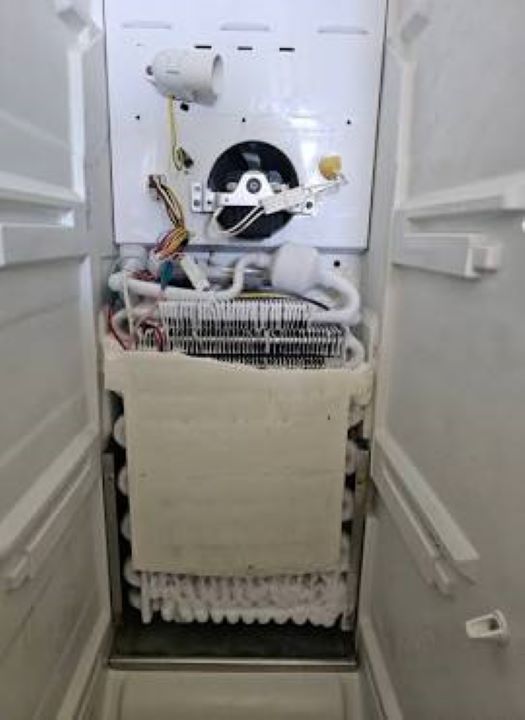 Inside view of refrigerator compressor and cooling system under repair by Sammy Appliance Repair in Queens