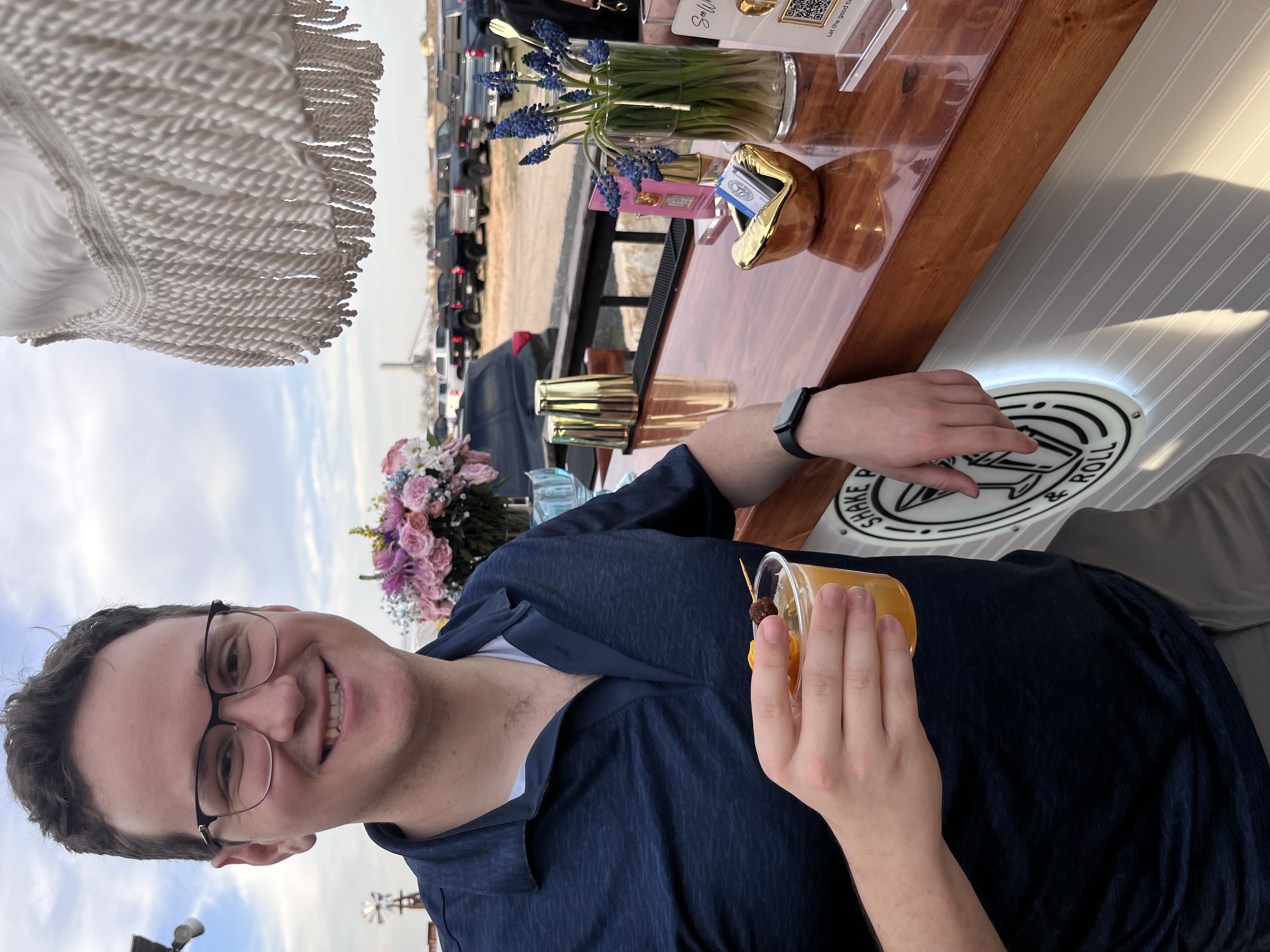 Guest leaning on the Shake Rattle & Roll mobile bar, enjoying the relaxed atmosphere of the Rollin Package beer and wine service, shown with the testimonial: "Their experience in the service industry shines through in their attention to detail." – Daniel R.