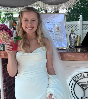 Bride enjoying a handcrafted mocktail in front of the Shake Rattle & Roll mobile bar, featured with the Mocktail Package testimonial: "So much effort was paid to even the smallest detail." – Leah R.