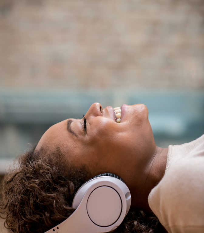 Woman relaxing with headphones, listening to a self-guided meditation from Piper