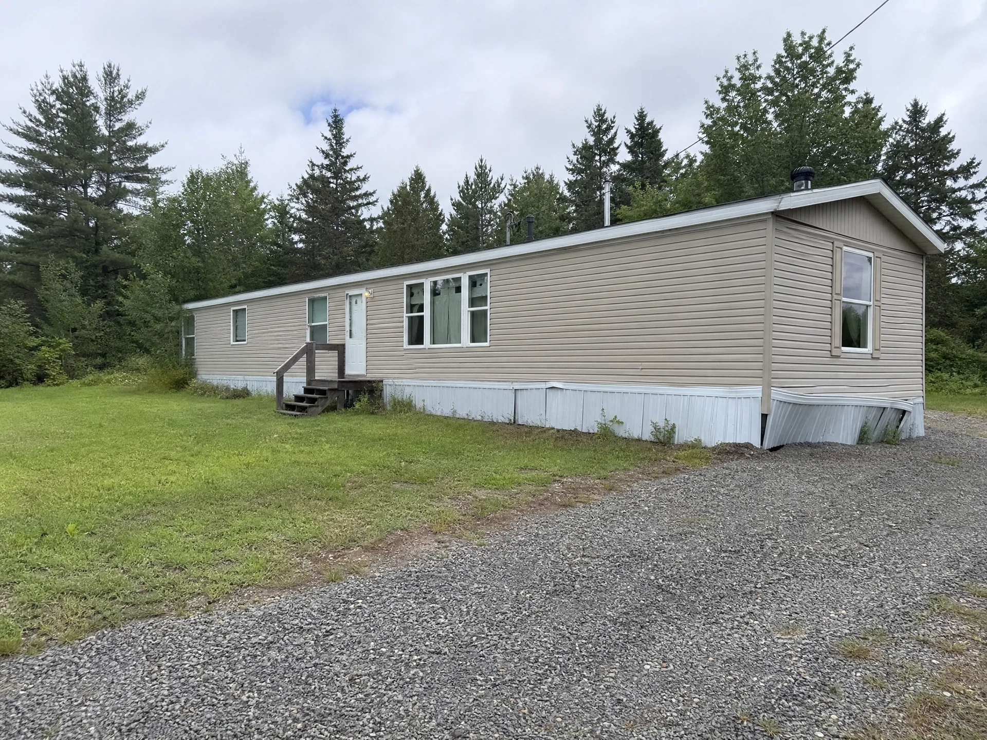 Older manufactured home on a rural lot in Oxford, Maine