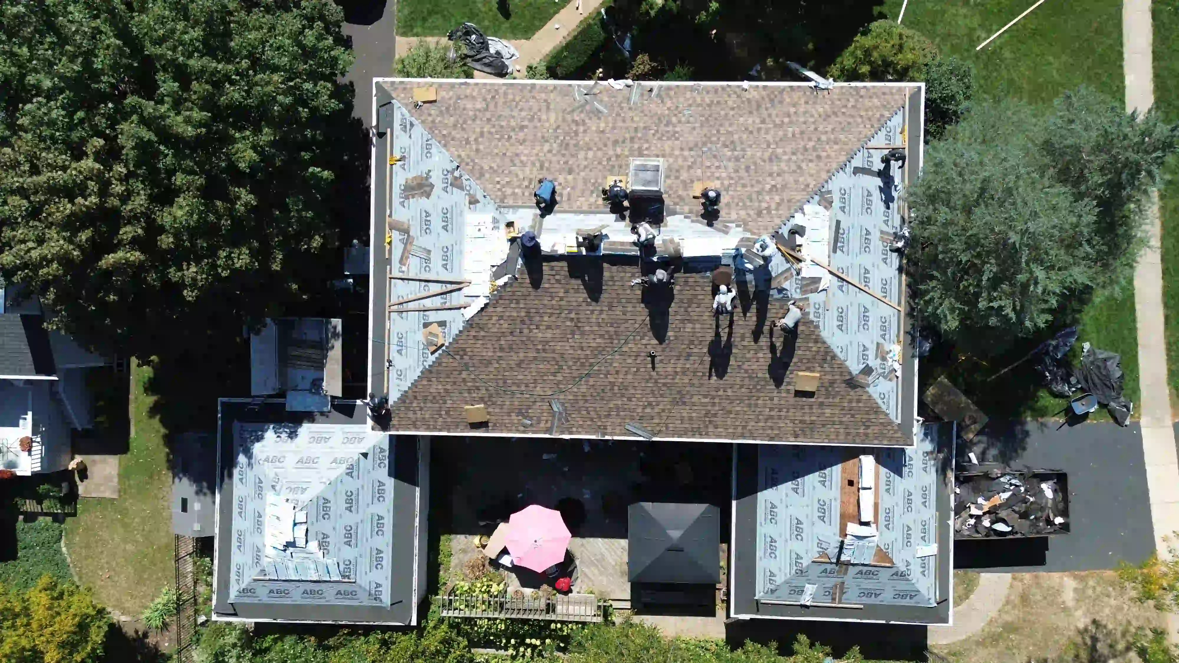 Red Oak Roofwork crew repairing roof with branded trailer on-site in Central Texas neighborhood