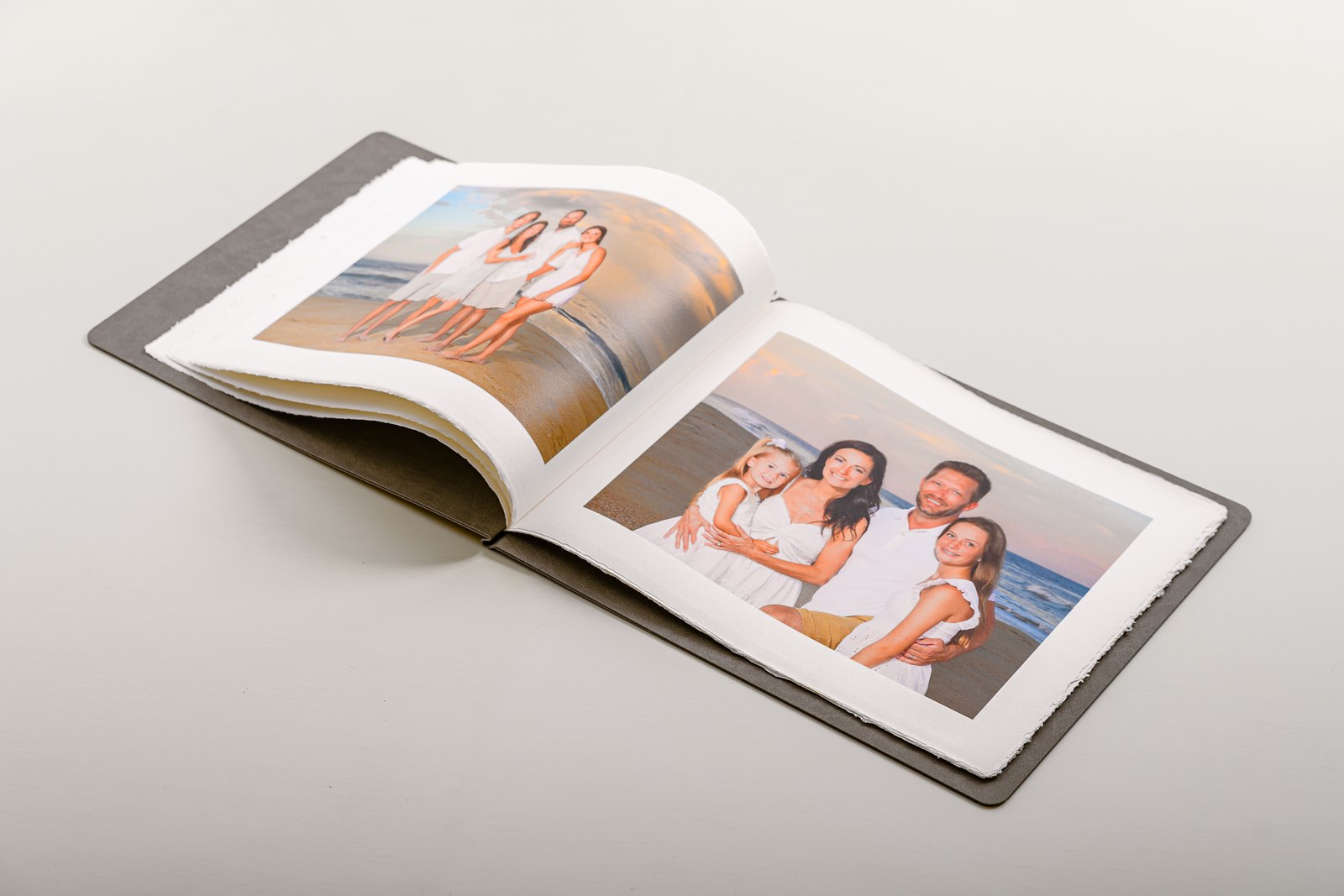 Storybook open to a family beach portrait spread on deckled Amalfi paper