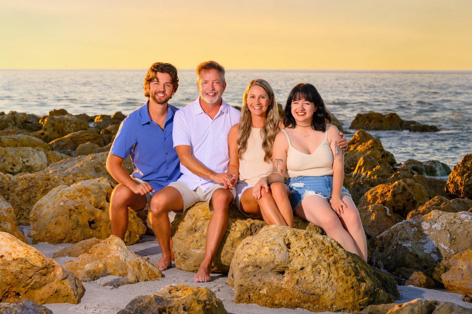 Family of four on coastal rocks in golden evening light