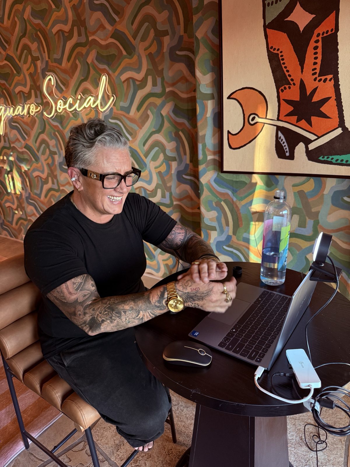 Jen Conkey laughing as she works at her laptop in front of a colorful mural