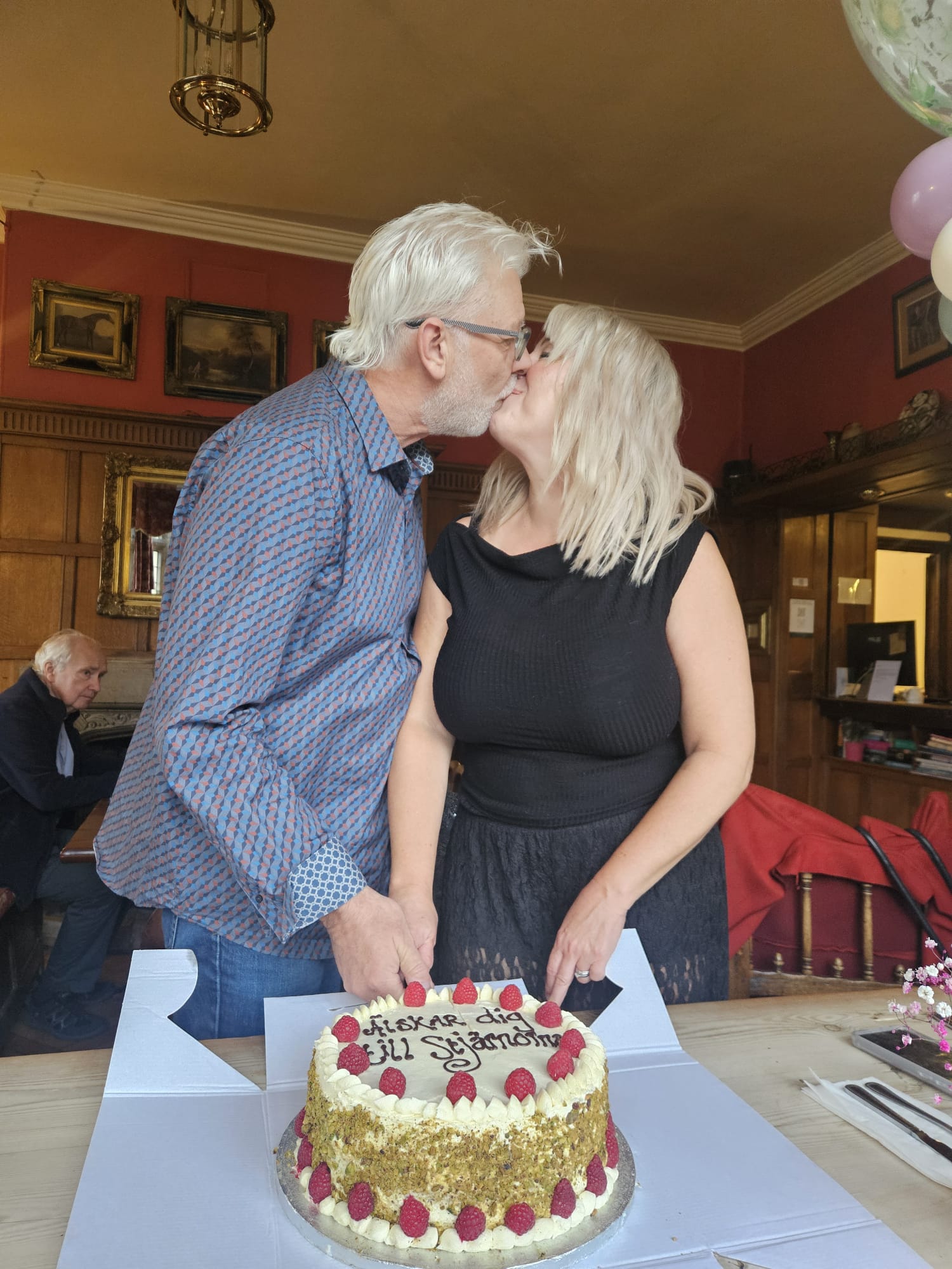 couple kissing while cutting a big celebration cake