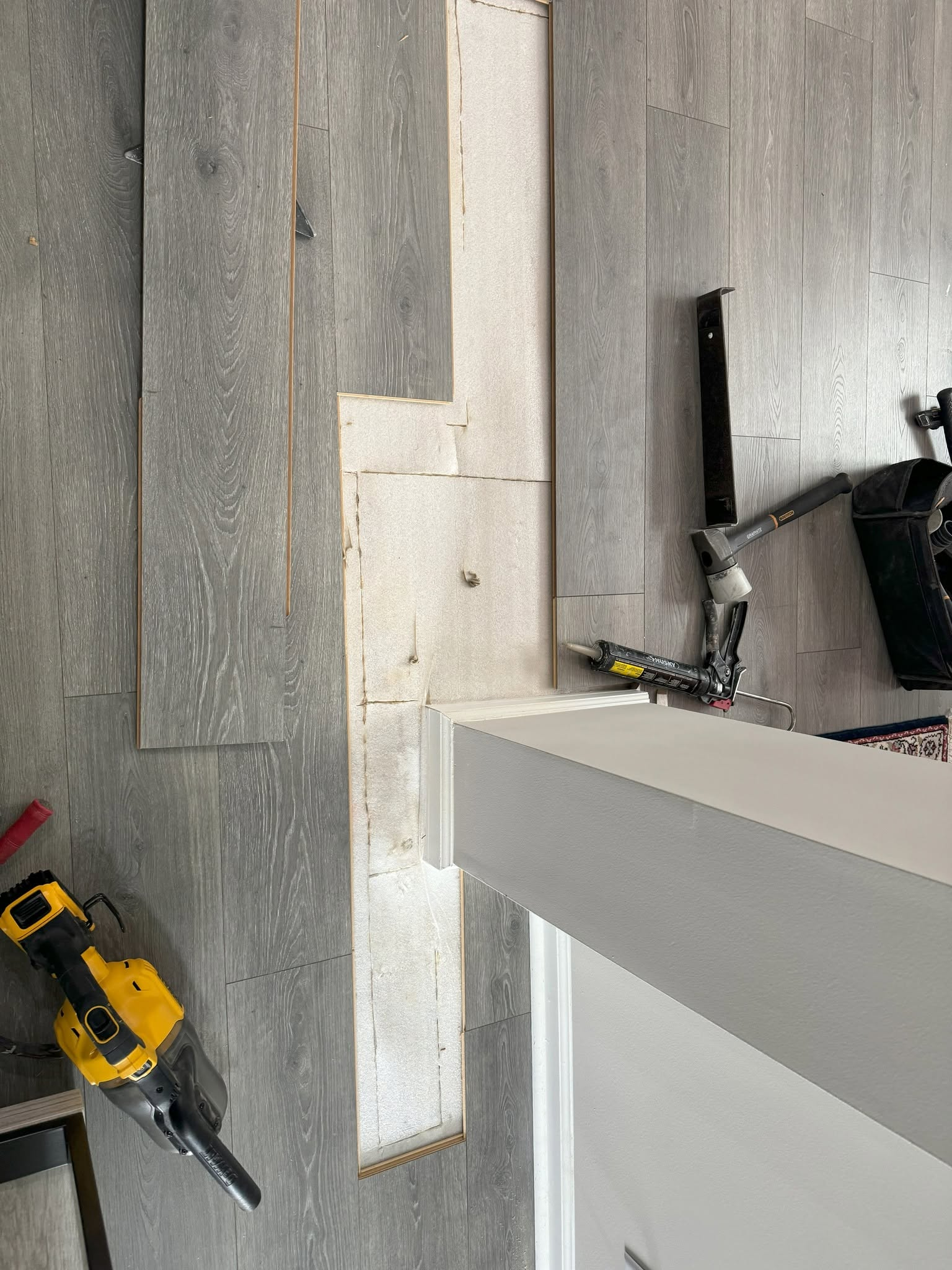 Laminate flooring repair area opened with tools nearby.