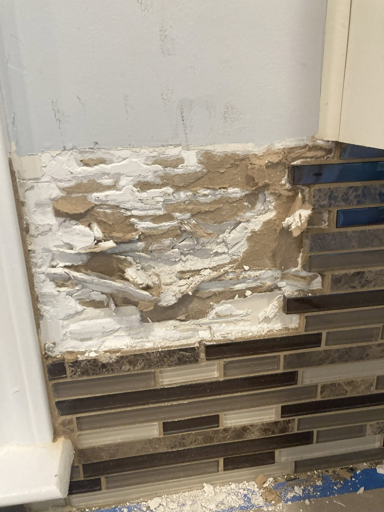 Old kitchen backsplash mosaic being removed from the wall.
