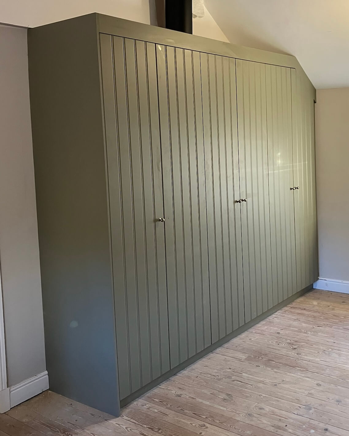 Bespoke fitted wardrobe installed in a period character home, designed to complement the room's existing architectural features by JAX Bespoke