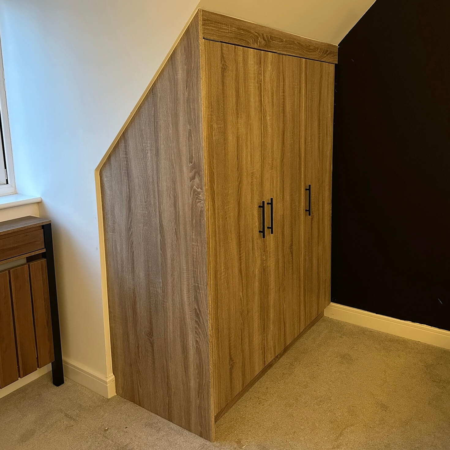 Made-to-measure fitted wardrobe built into an awkward loft room with sloping ceiling and angled walls, by JAX Bespoke