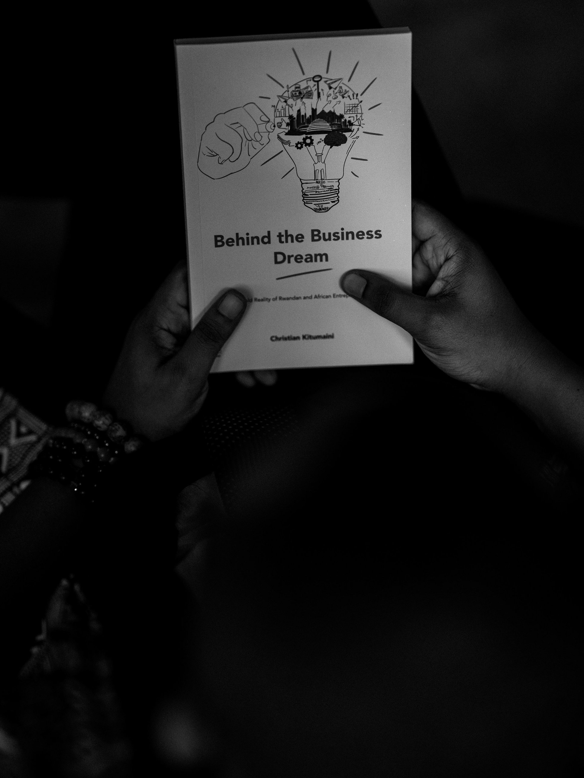 Christian Kitumaini's hands holding a copy of Behind the Business Dream