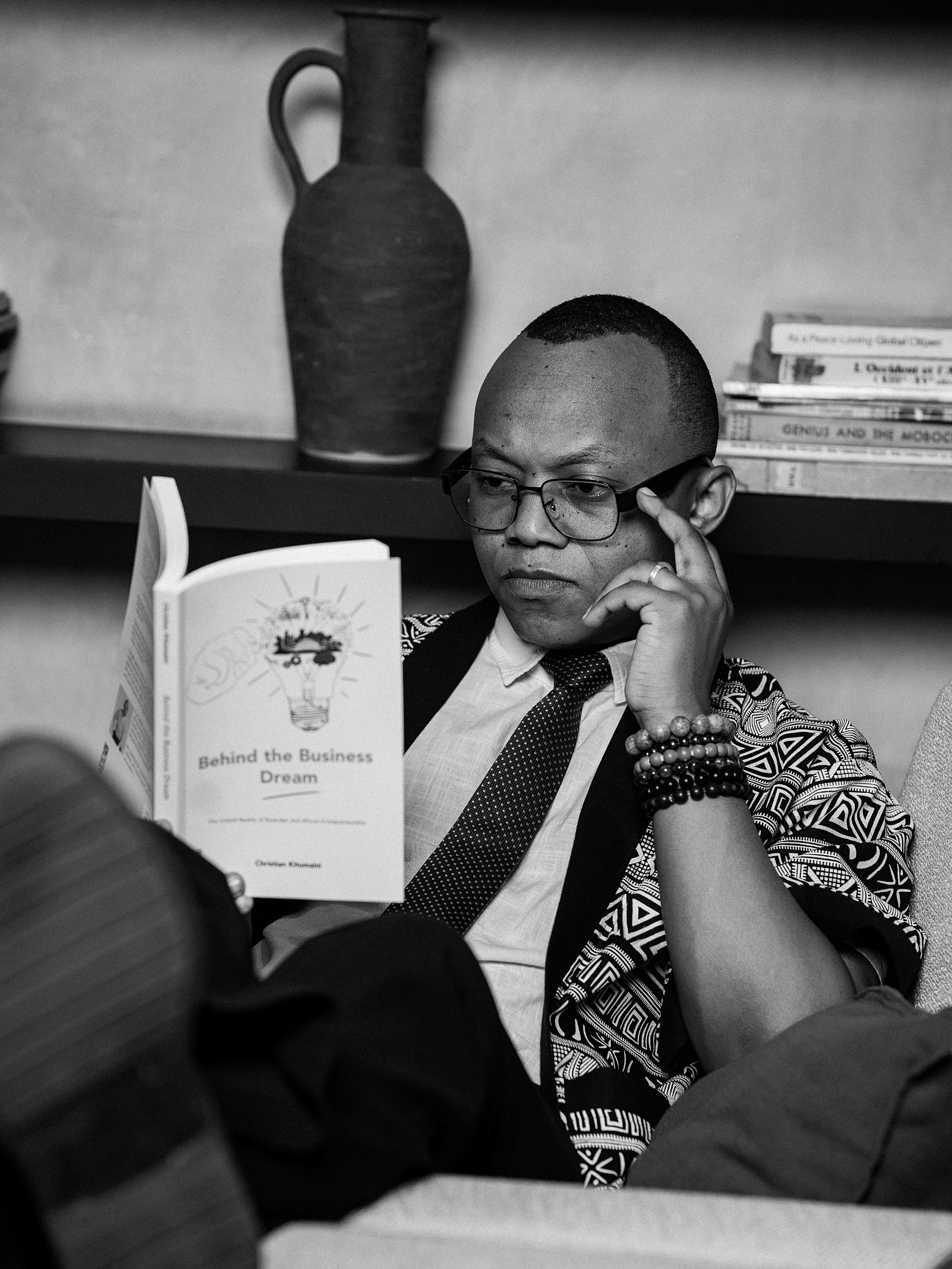 Christian Kitumaini reading an open copy of Behind the Business Dream