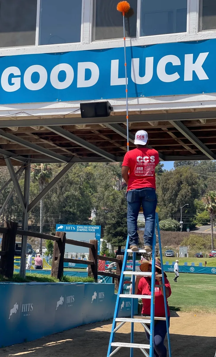 CCS worker performing event venue cleaning on ladder