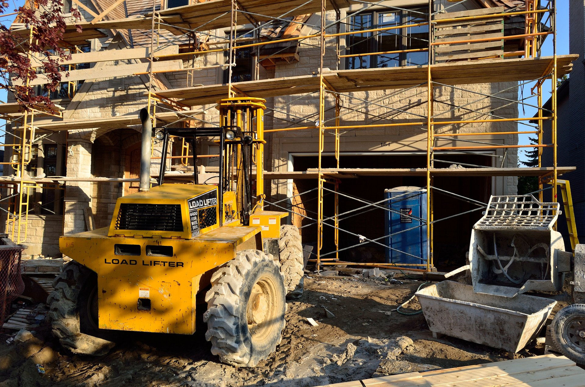 House under construction with scaffolding and a yellow telehandler on a residential lot in North York, Toronto