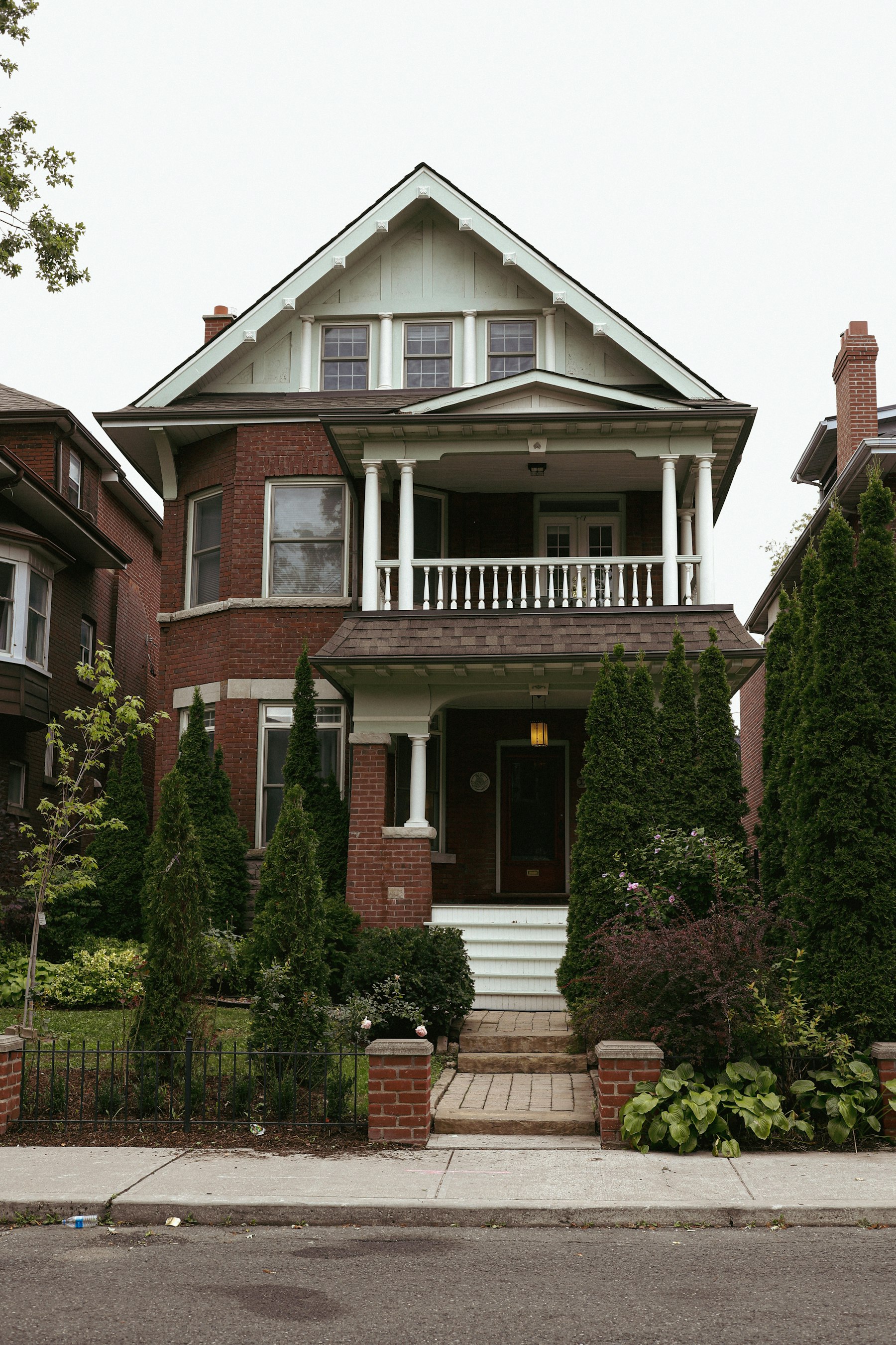 Red-brick Toronto multiplex with white porch and balcony on an East York residential street Red-brick Toronto multiplex with white porch and balcony on an East York residential street