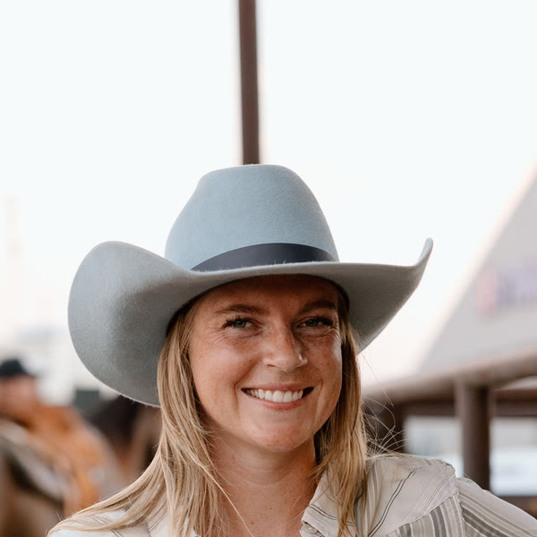 Bailey Ryan-Thompson in a cowboy hat at the arena fence