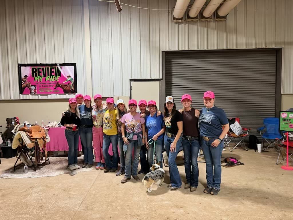 Stall High riders and coaches together in pink team caps at an event