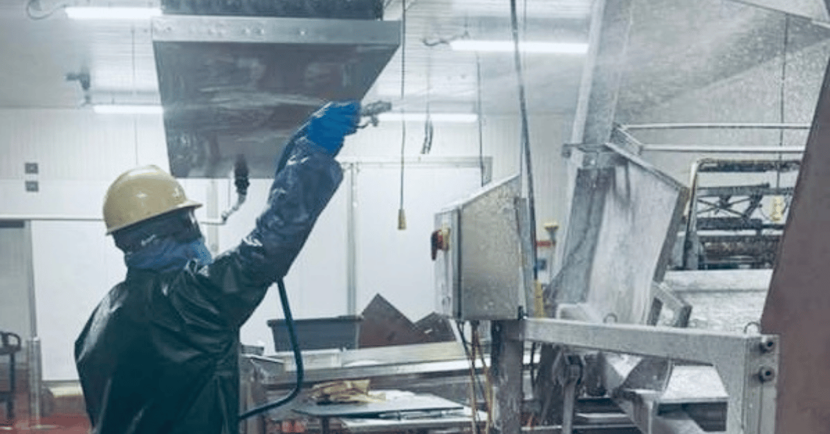 Elite crew member applying foam to food processing equipment during overnight sanitation