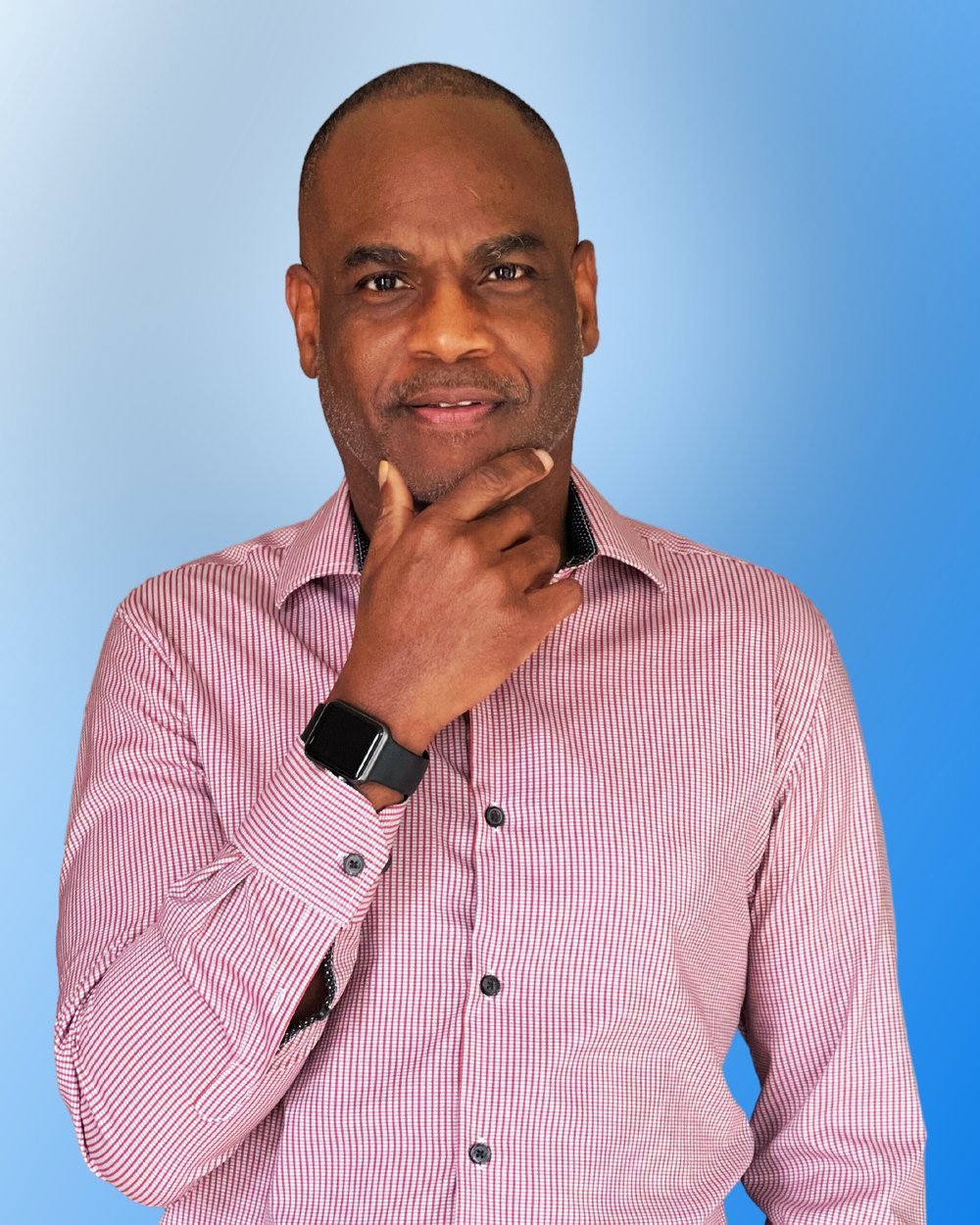 Dwayne Golden in a pink striped shirt with his hand on his chin