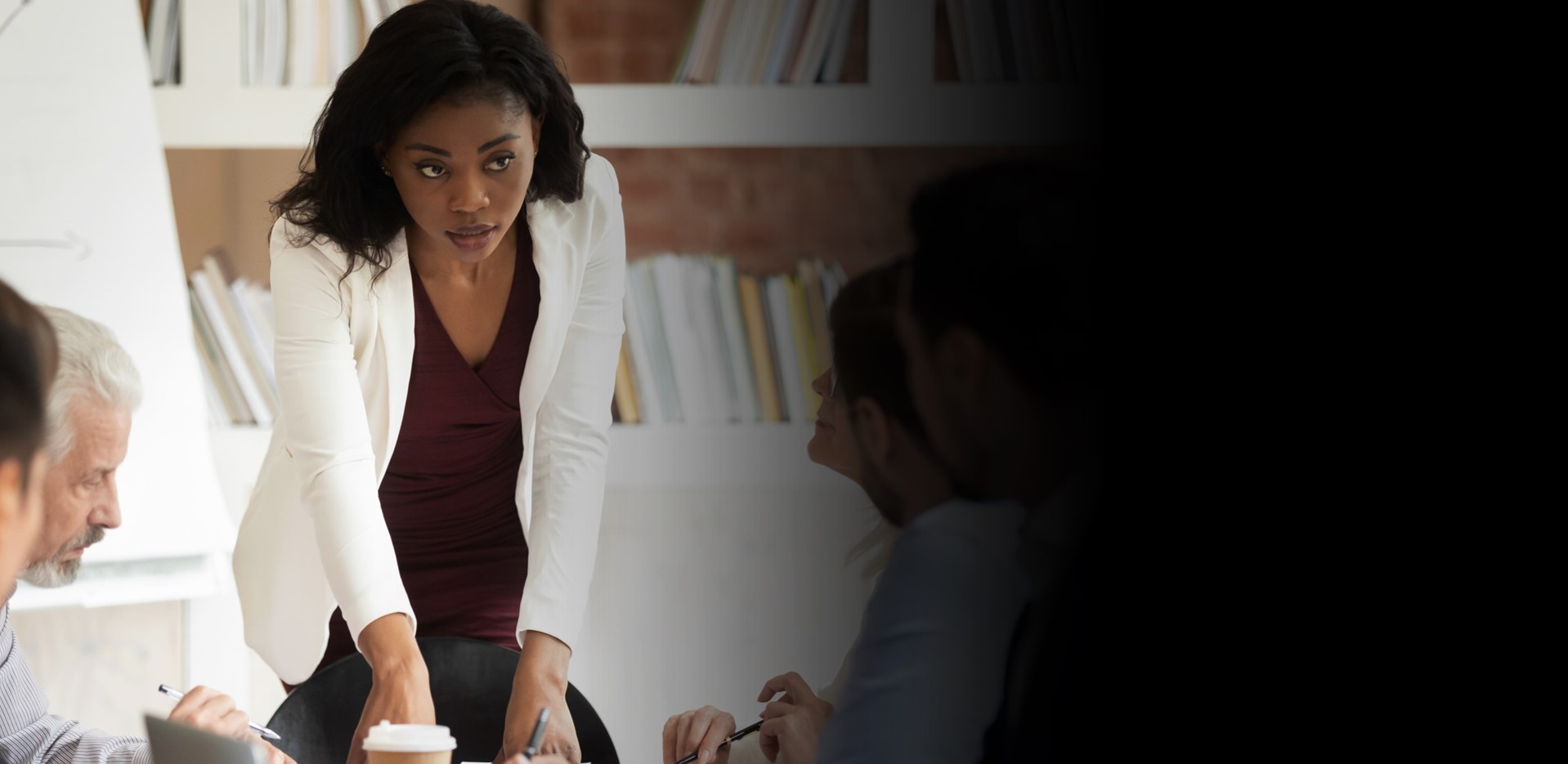 A young Black leader presenting to colleagues around a boardroom table