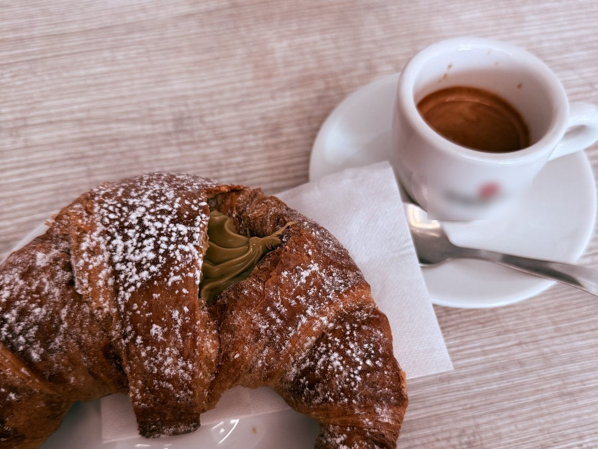 Espresso and a pistachio croissant on a café table