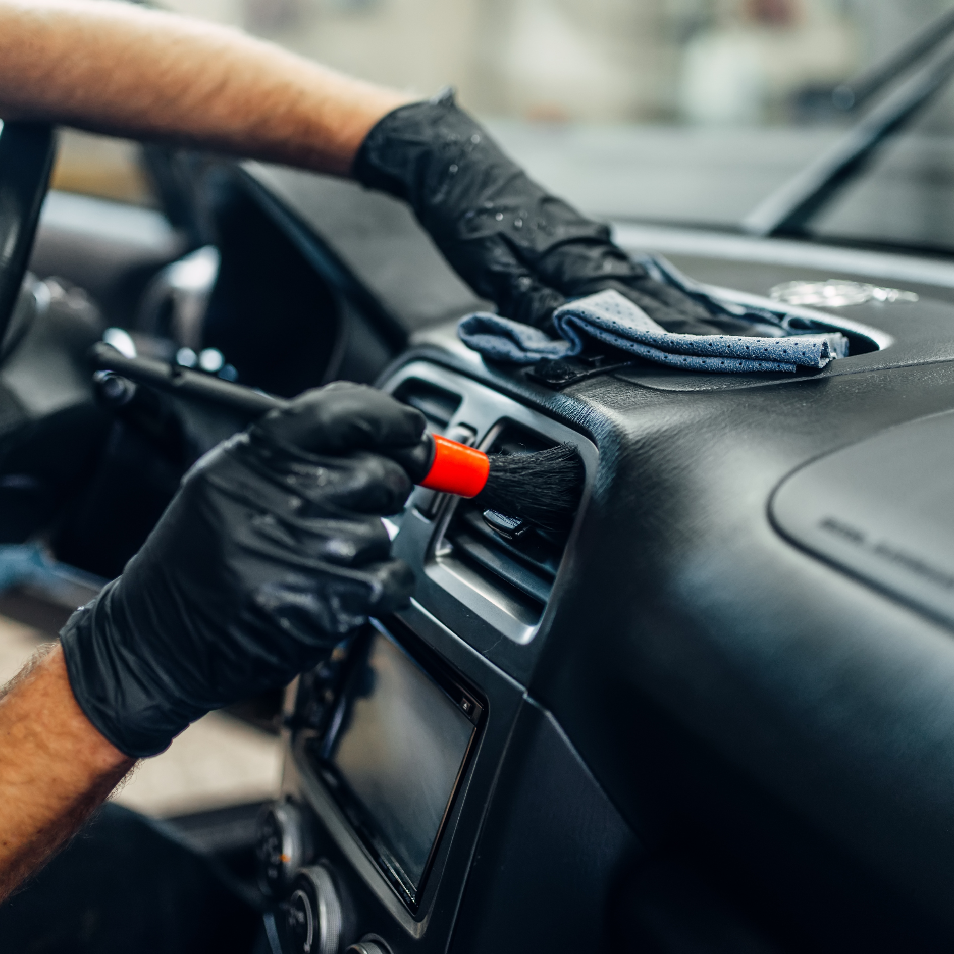 Professional polishing the exterior of a dark vehicle