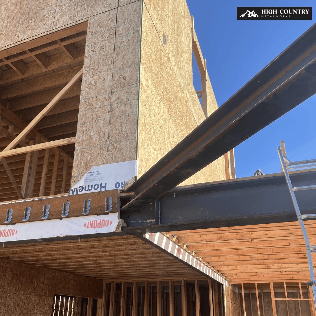 Construction site of a wooden building with exposed beams and structural steel frame support under a clear blue sky.