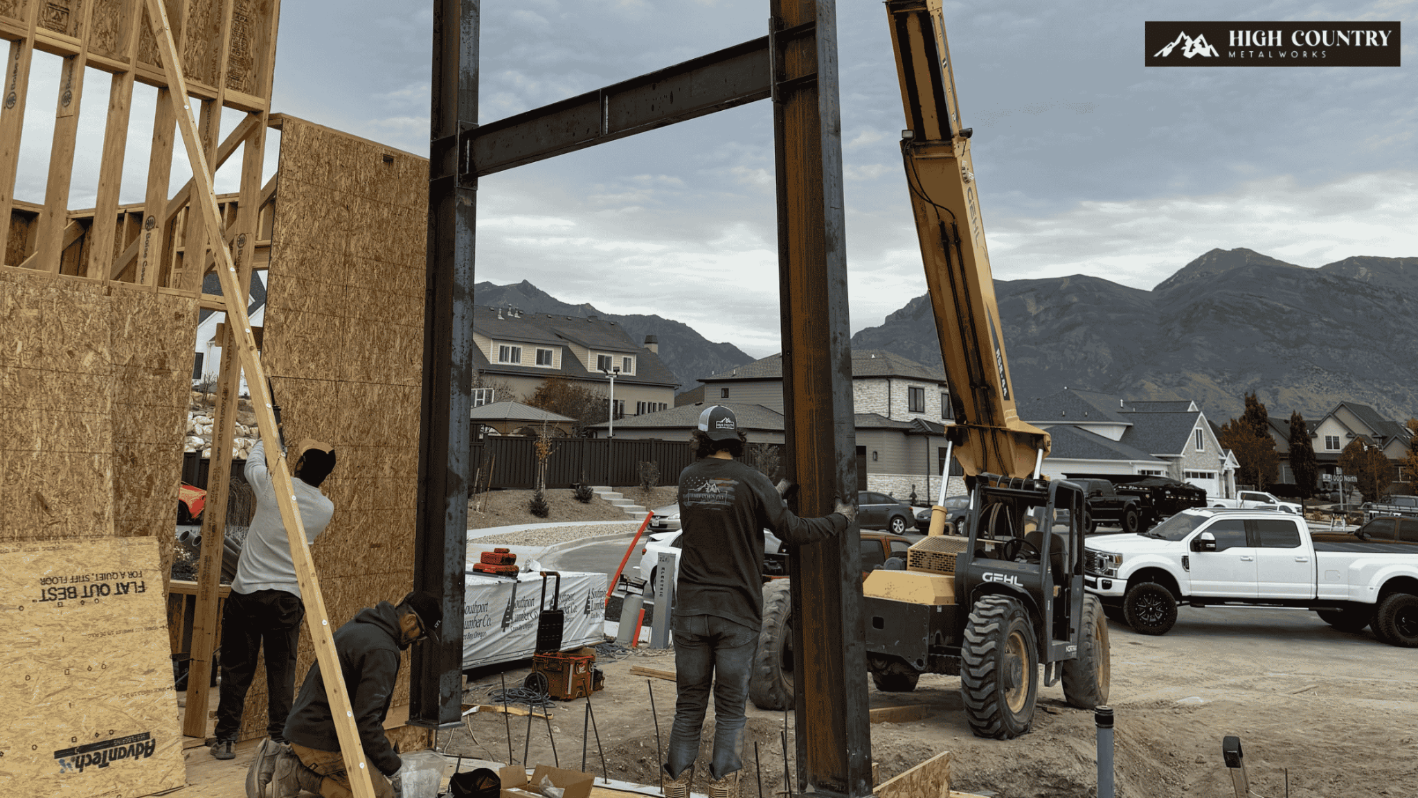 Construction workers operate a crane to lift structural steel beams for a house under construction. Construction workers operate a crane to lift structural steel beams for a house under construction.
