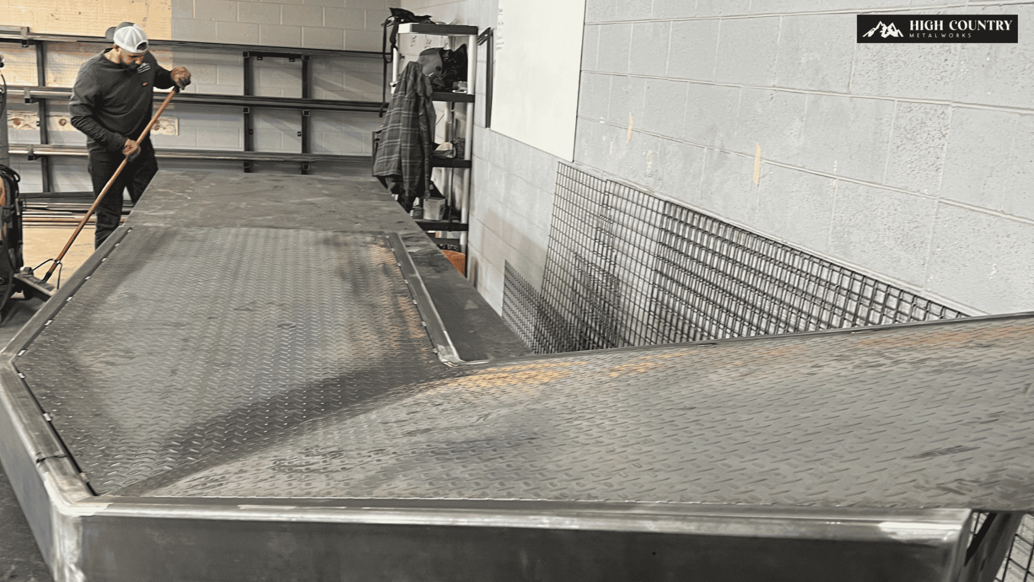 A fabricator inspects a metal ramp in a warehouse, ensuring it meets code compliance before fabrication begins.