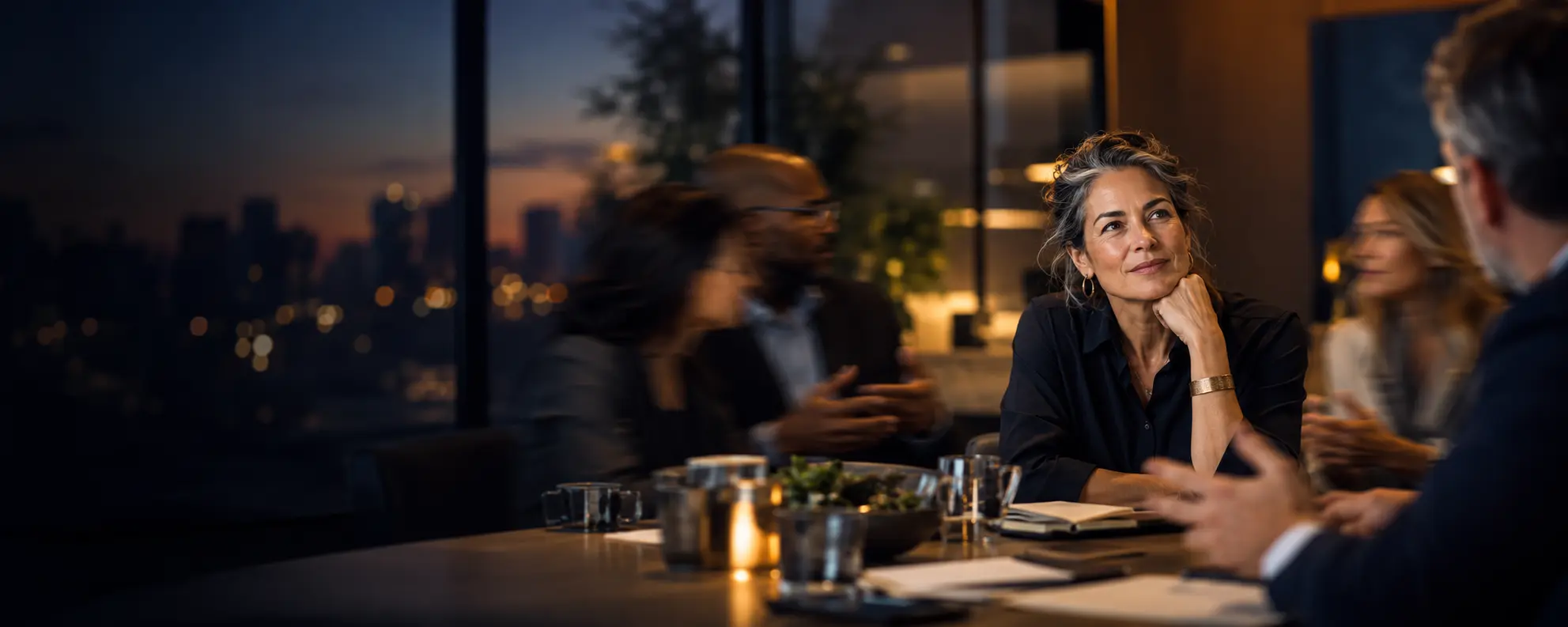 A composed leader listening thoughtfully while a busy leadership conversation moves around her