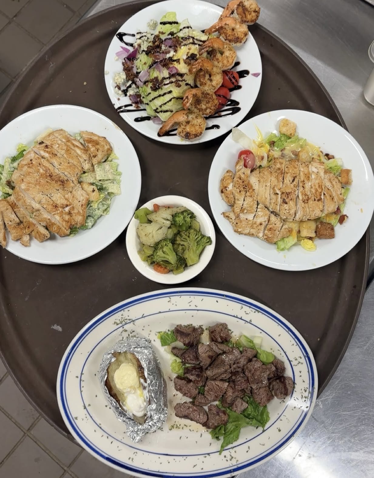 A tray of shared plates at Haifa's &mdash; grilled shrimp wedge salad, chicken Caesar, house salad and steak morsels with a loaded baked potato