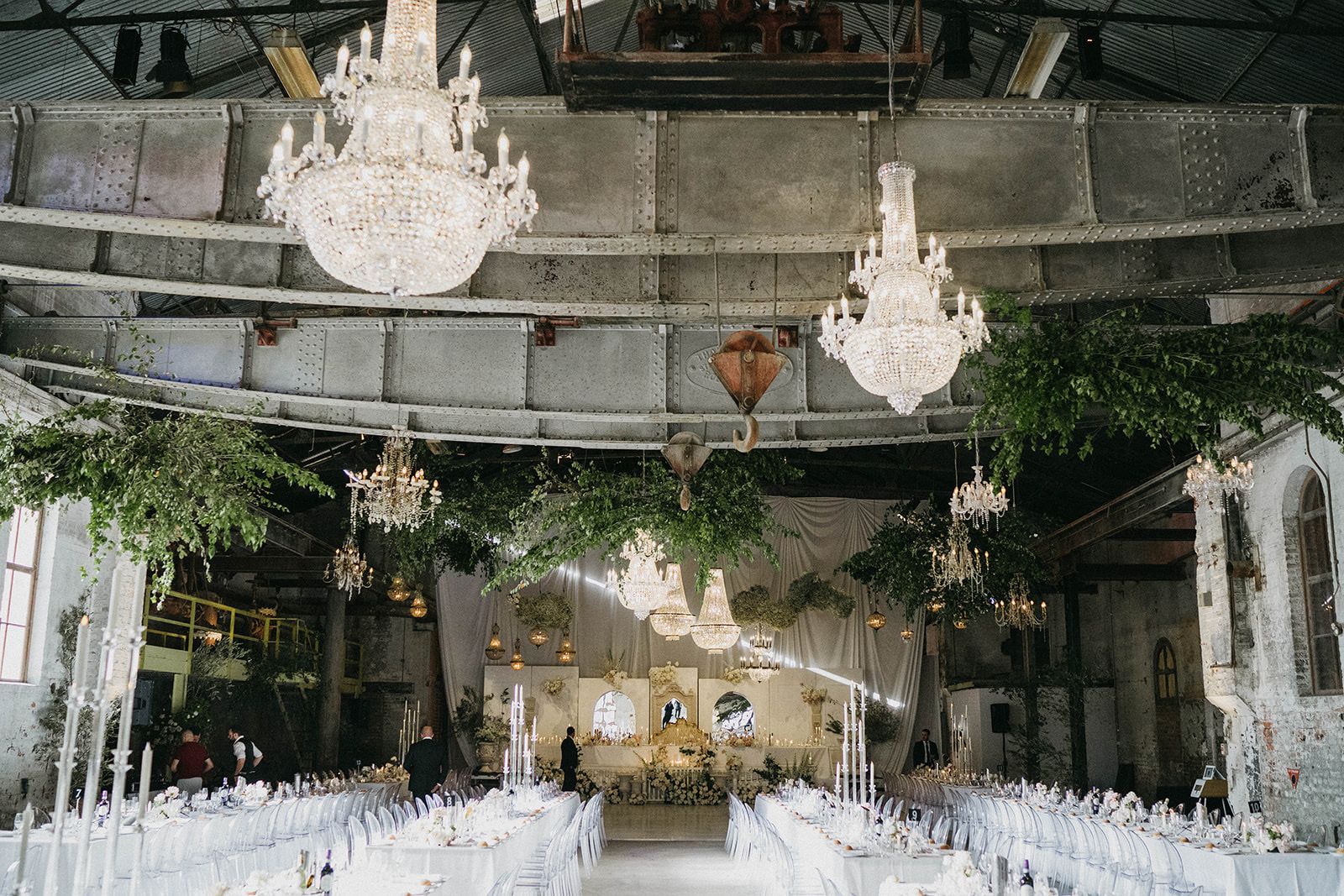 Chandeliers hanging from the old crane rails above a wedding reception