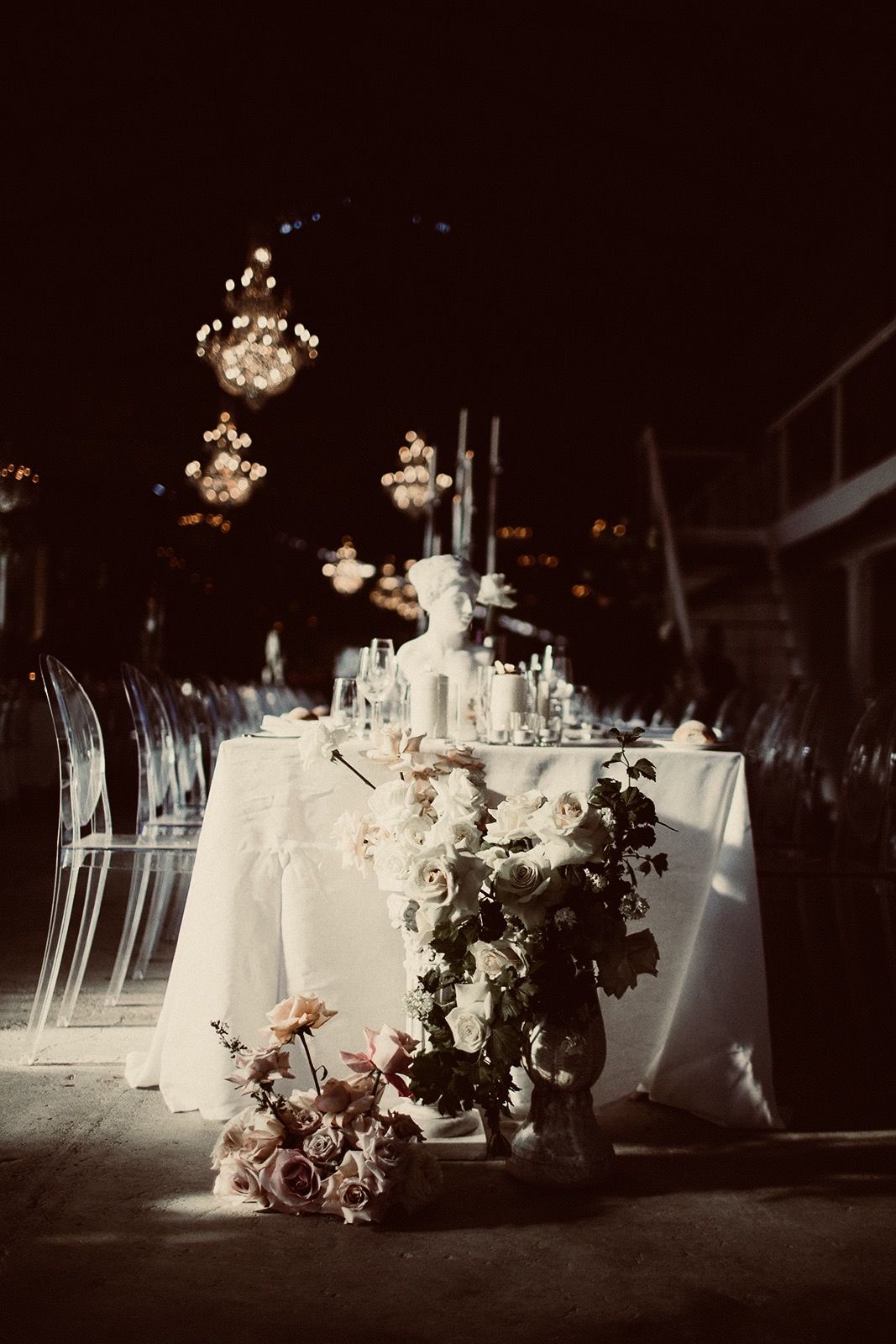 A white linen table with candles and roses under chandeliers