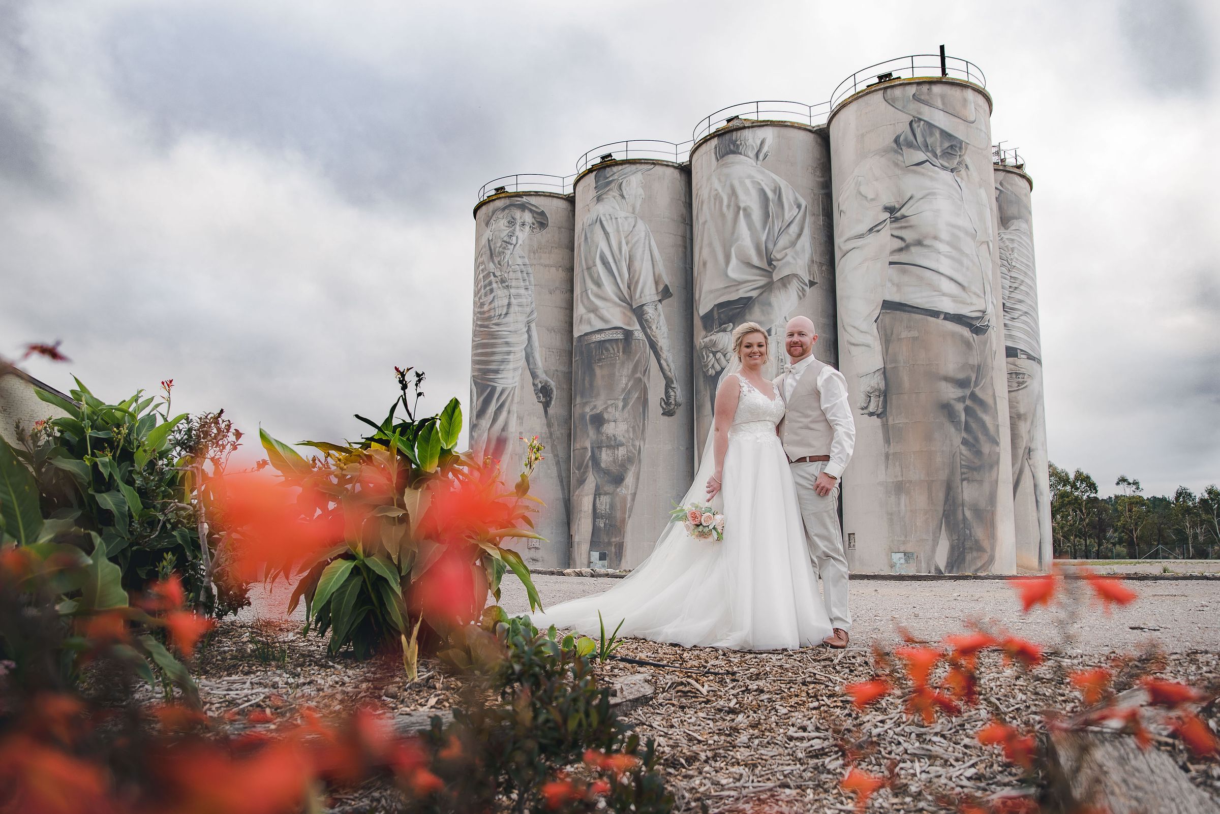 A bride and groom in front of the painted silos at The Foundations