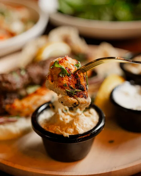 Chicken skewer dipped into garlic sauce