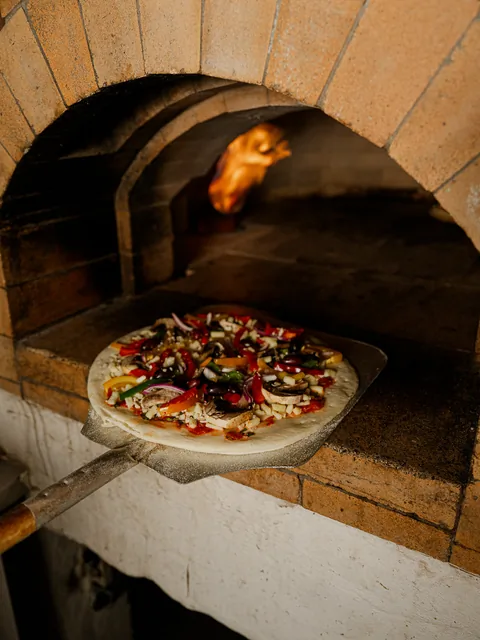 Pizza going into the wood-fired brick oven at Beit Baytak