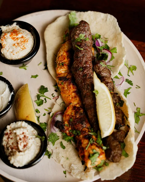 Kafta and tawook skewers on bread with hommus and garlic dip