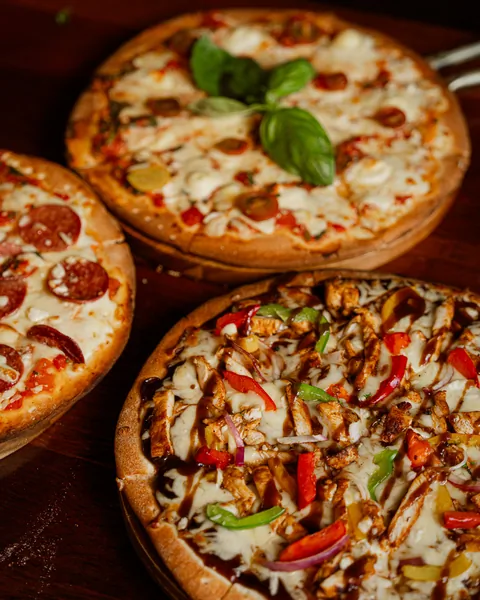 Pepperoni, margarita and BBQ chicken pizzas on the table
